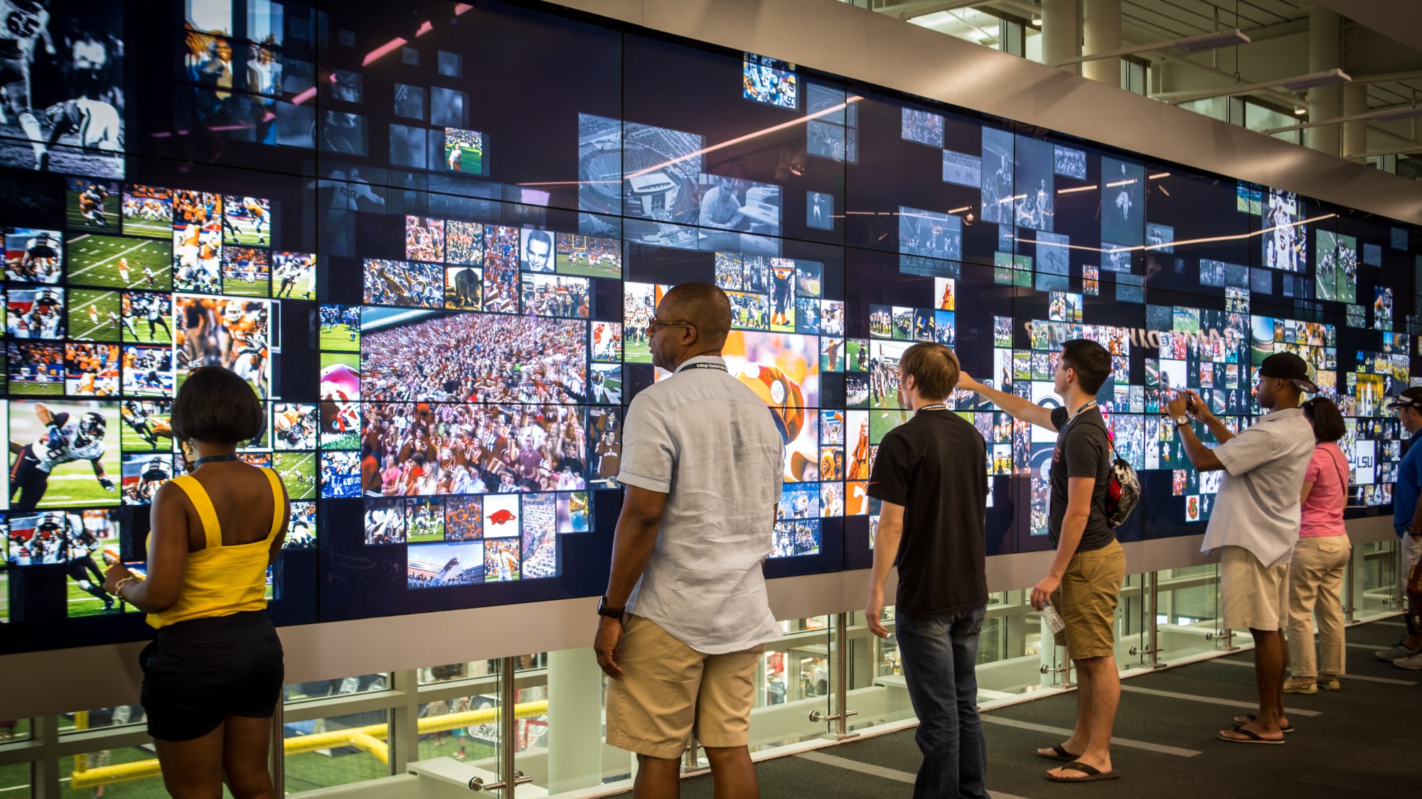 Des visiteurs interagissent avec l’écran tactile géant du College Football Hall of Fame